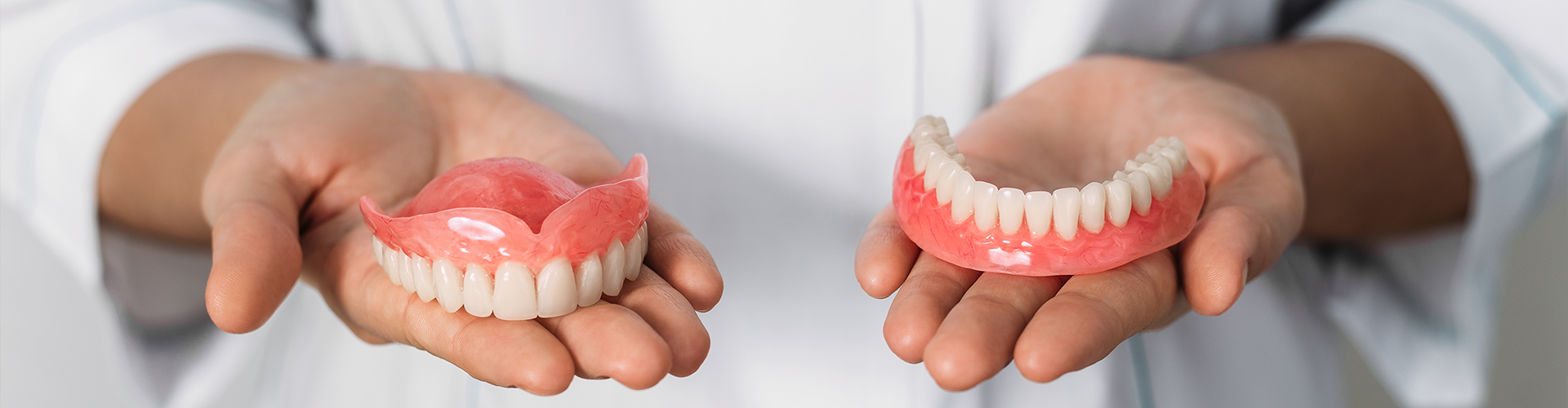 hands holding upper and lower dentures